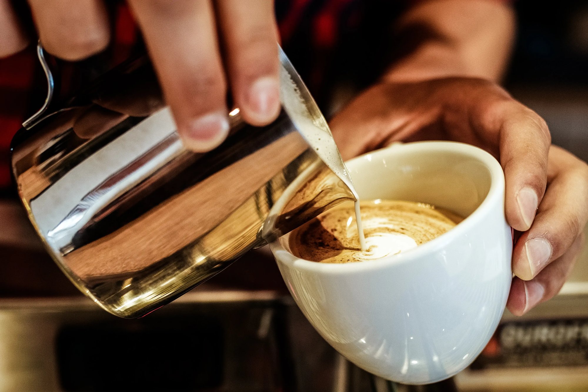 A barista at the Electrosonic IAAPA Expo booth pouring a patron a cappuccino.